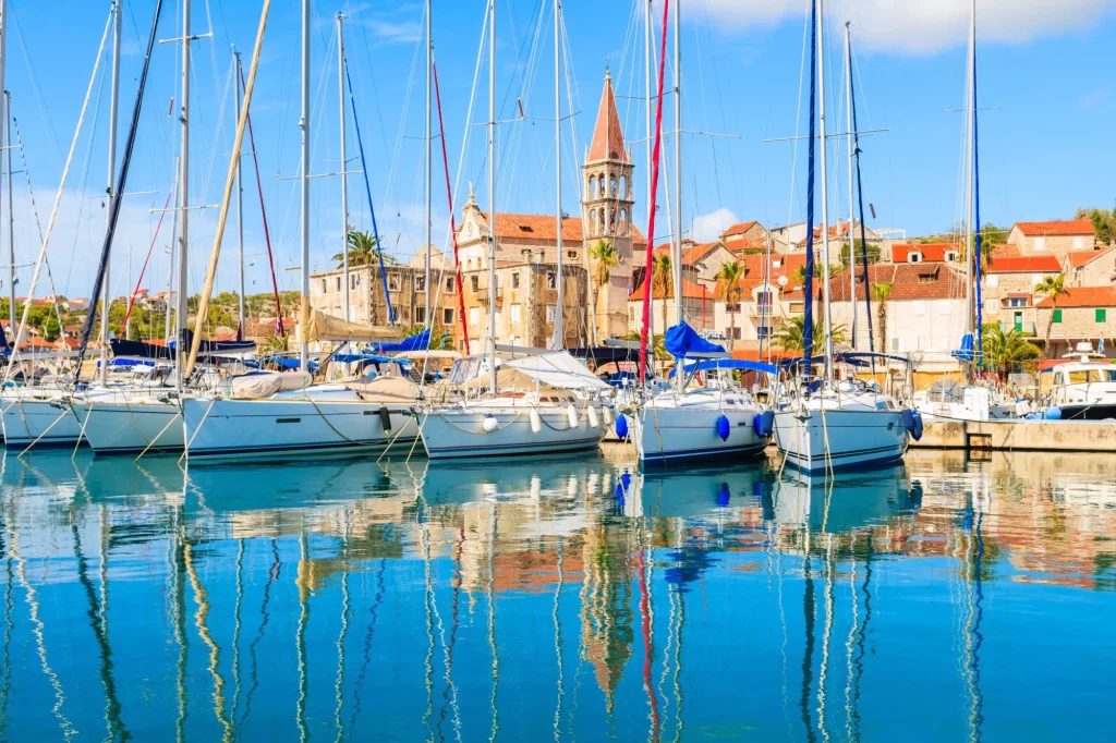 Reflektion av segelbåtar som ankrar i vackra Milna hamn med kyrktorn i bakgrunden, ön Brac, Kroatien